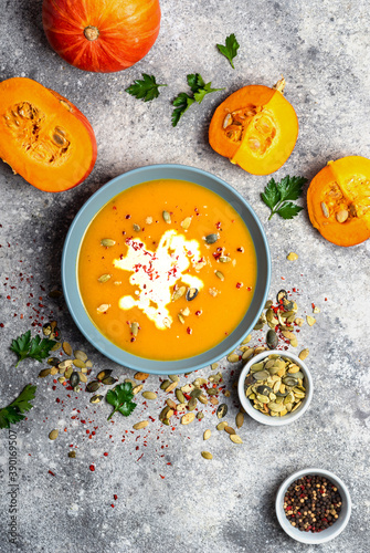 Pumpkin soup with cream and seeds on grey stone background. Top view.