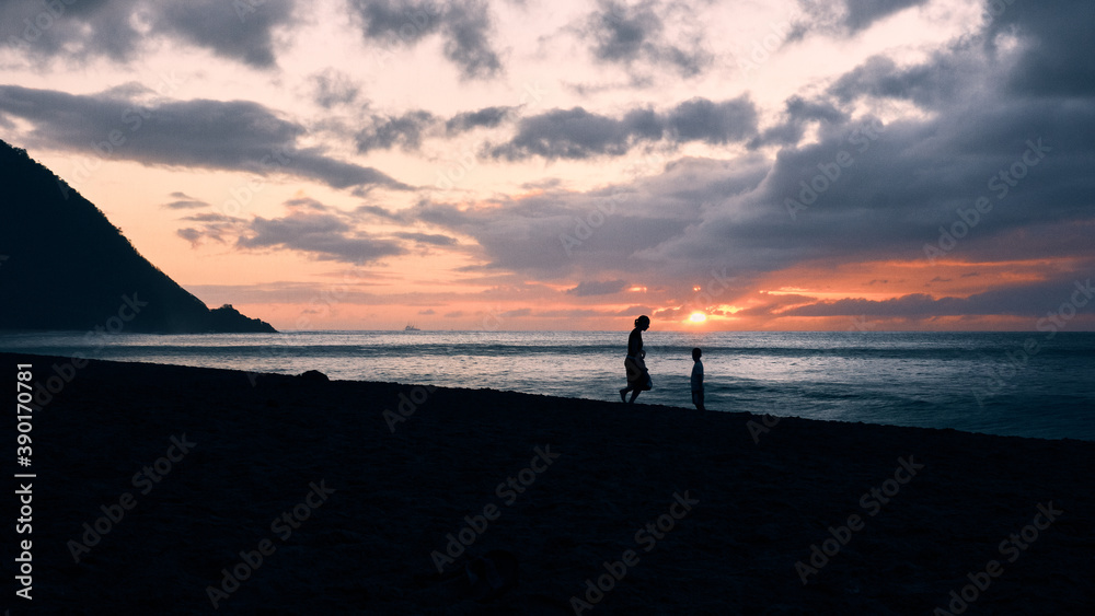 Femme et son enfant pendant un coucher de soleil sur une plage