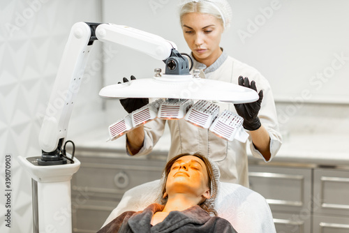 Young woman doing led light therapy on her face with a doctor at luxury medical office photo