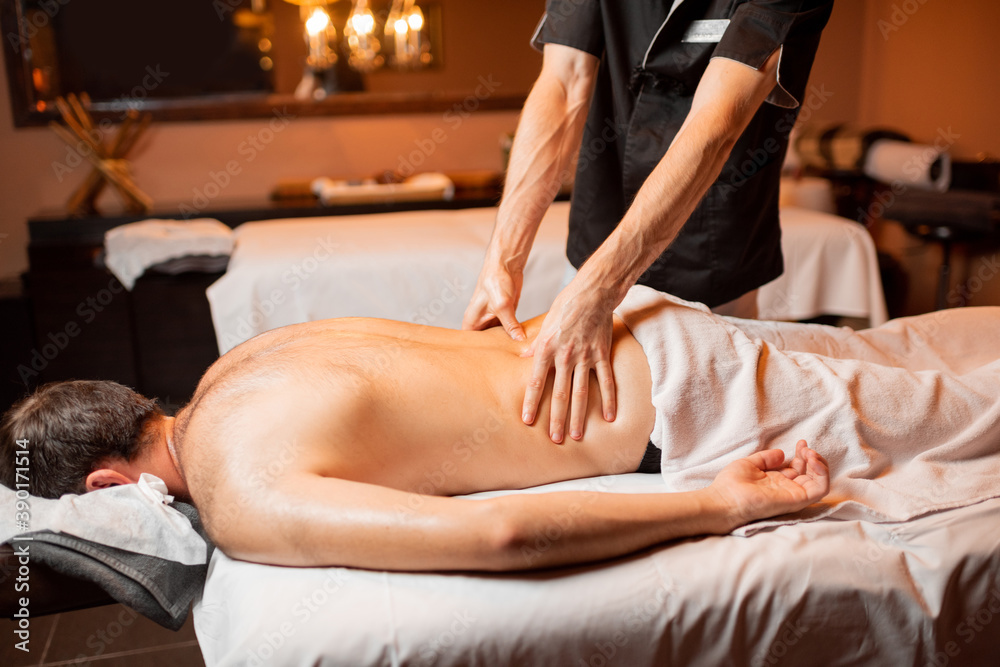 Fototapeta premium Man receiving a deep massage on his back from professional therapist at luxury spa salon