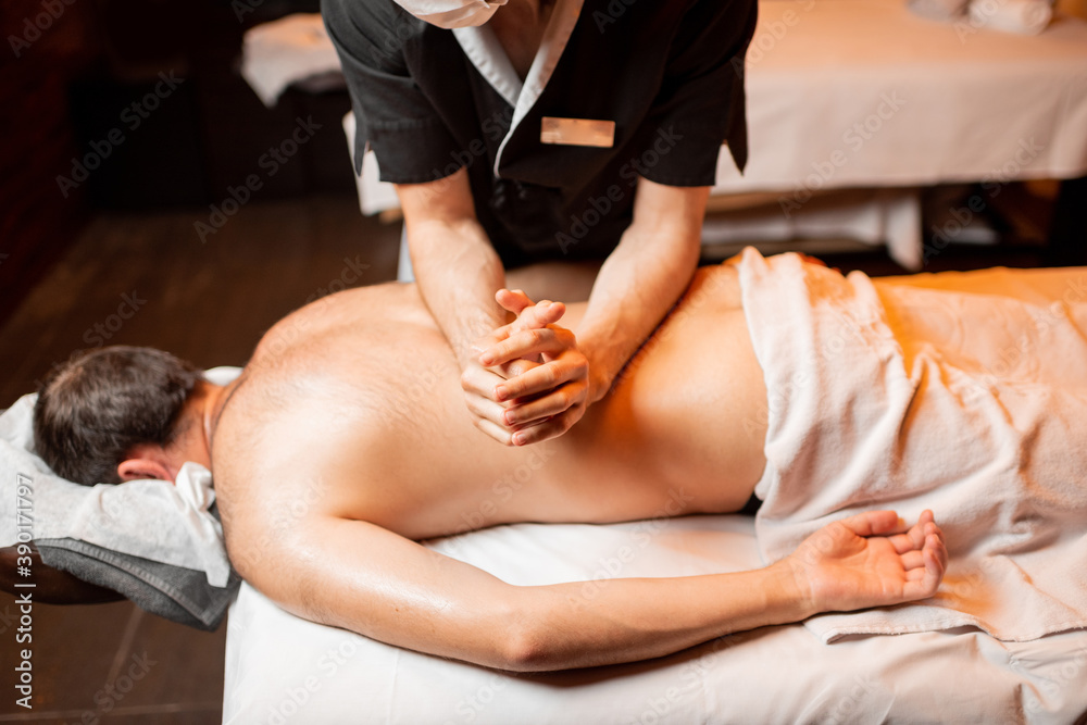 Fototapeta premium Man receiving a deep massage on his back from professional therapist at luxury spa salon