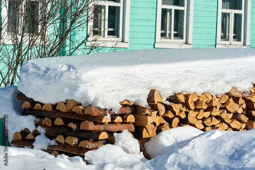 Wood piled in a woodpile under the snow in winter