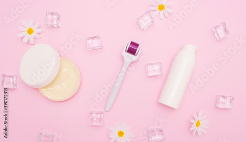 Body and skin care, cosmetology. White plastic containers for cosmetics and creams and mesoroller. Ice cubes, free space for text, top view.
