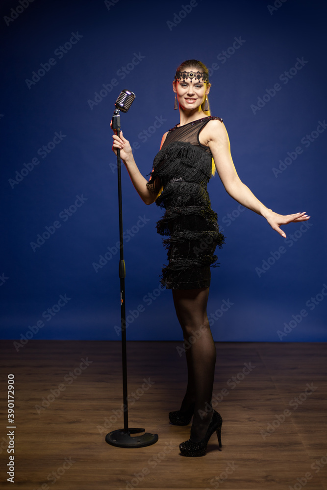 Young woman with long hair in a black dress in a retro style on a blue