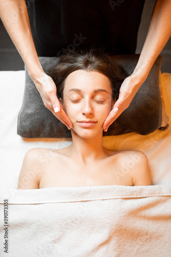 Young woman receiving a facial massage, relaxing at Spa salon, view from above
