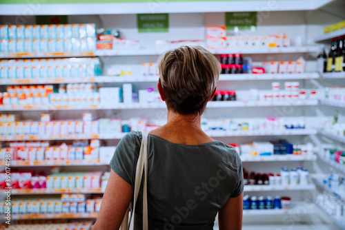 фотографія Woman walking towards shelf searching for cold and flu medication for sick husband