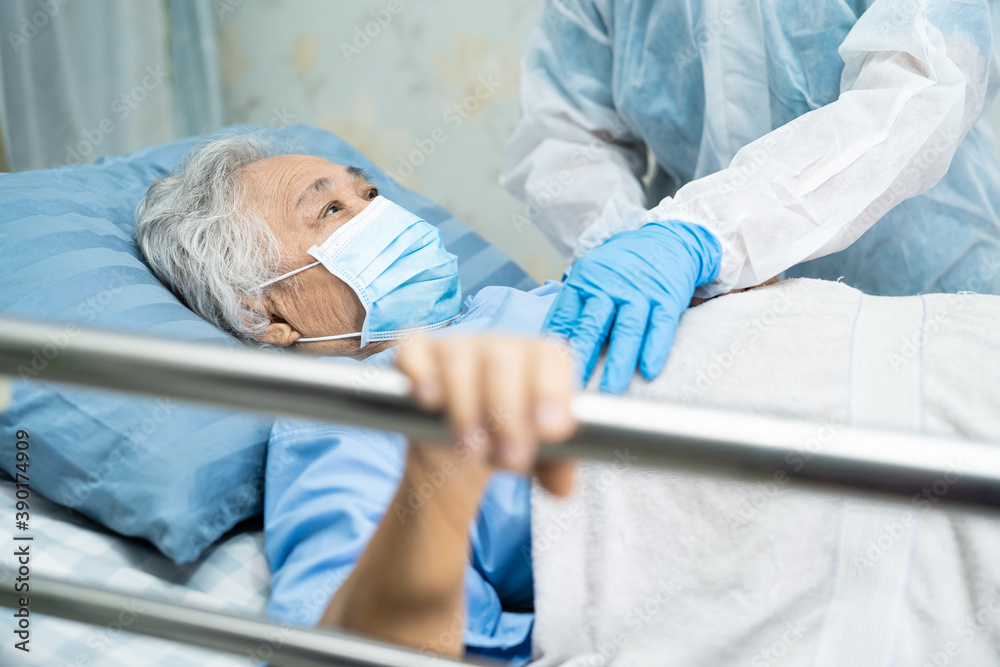 Obraz premium Doctor wearing PPE suit to checking Asian senior or elderly old lady woman patient wearing a face mask in hospital for protect infection Covid-19 Coronavirus.
