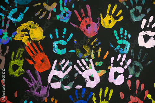 Drawing of human palms on a black wall. Multicolored hands on a black background close-up.