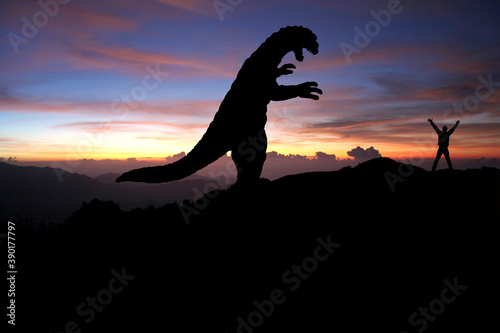 Silhouette eines Godzilla-artigen Monsters und ein Mensch  © SINNBILD Design