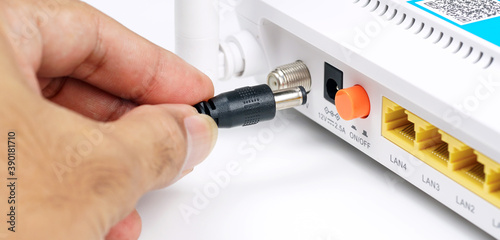 Man's hands to Power Cable connected on the router. 