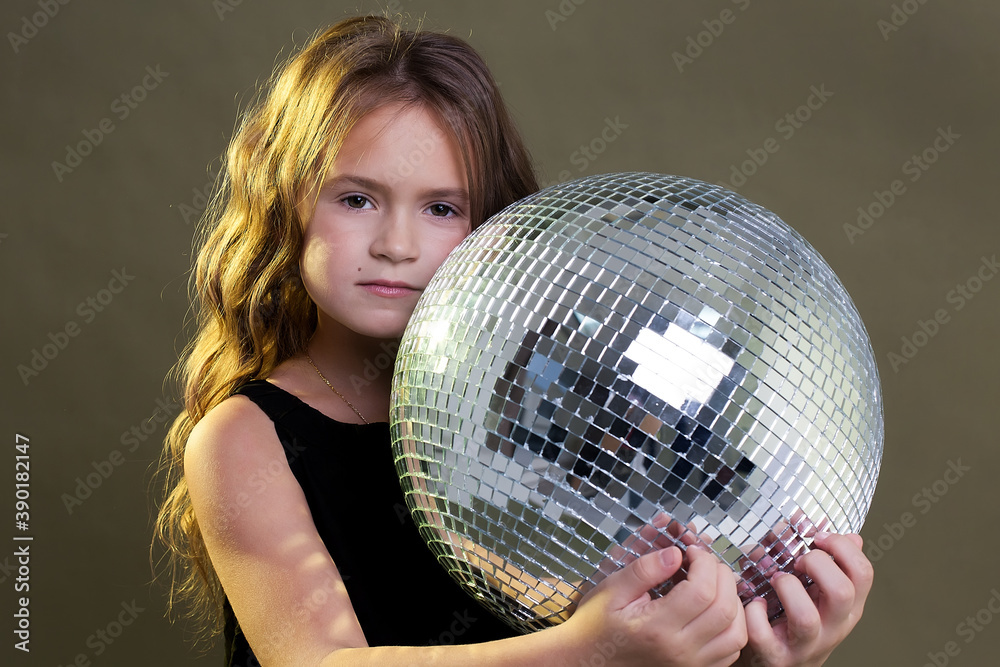 little happy baby girl holding a disco ball on a gray background. new year little happy baby girl holding a disco ball on a gray background. new year
