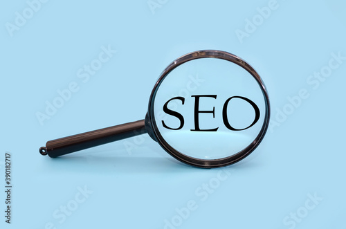 "SEO" through a magnifying glass on a blue background.