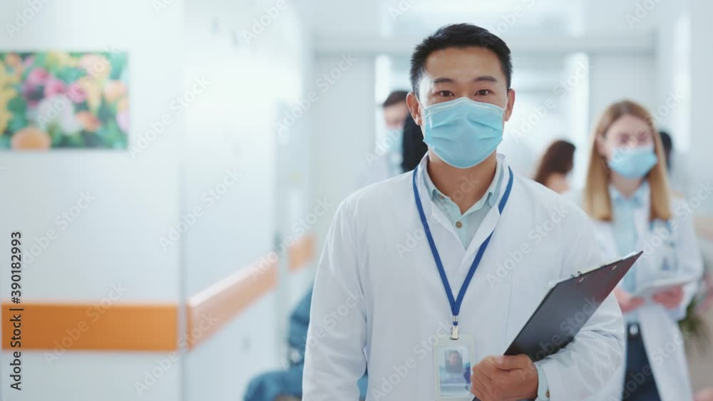 Asian adult man wearing suit and face mask in the hospital. Portrait of professional man inside the clinic. Medical staff. Healthcare. Pandemic, coronavirus, lockdown concept.