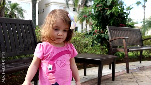 Garotinha brincando no jardim em tarde ensolarada e correndo em direção ao pai. Video em câmera lenta.