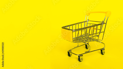 Empty shopping grocery cart on yellow background. Concept of business, shopping, black friday sales.