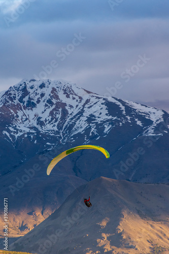 Paragliding against snow-capped Andes mountains during winter season in Esquel, Patagonia, Argentina