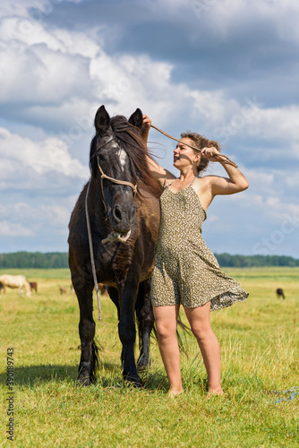 A girl puts a rope halter on a horse on the field.