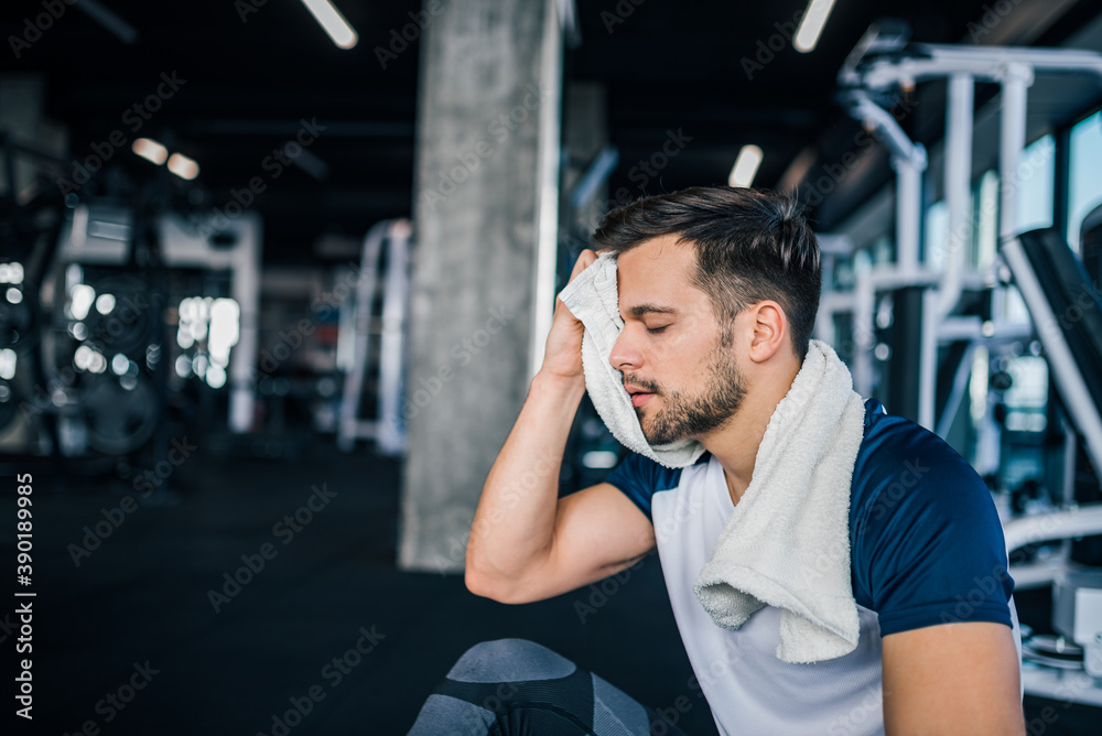 Portrait of a handsome athlete wiping sweat at the gym. - obrazy, fototapety, plakaty 