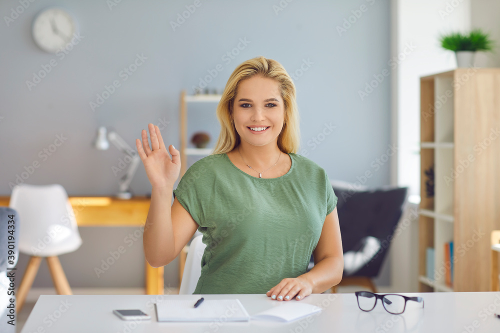 Smiling blonde woman greeting somebody and looking at camera during online lesson or video call
