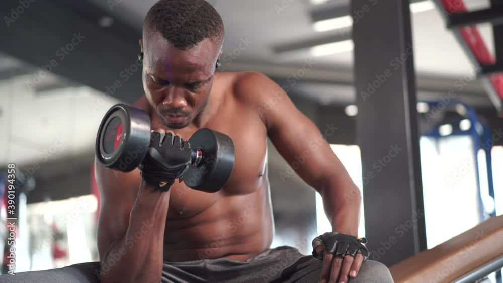 Fitness man pumping up arm muscles with dumbbell at gym Fitness man pumping up arm muscles with dumbbell at gym