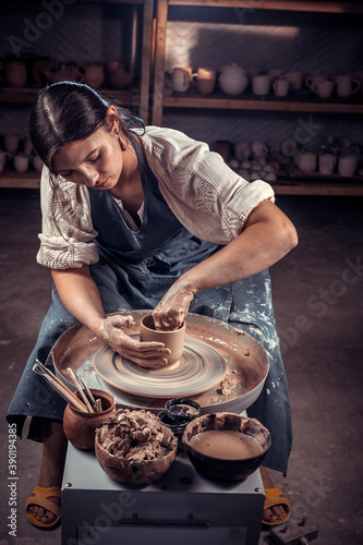 Charming pottery working on potter's wheel with raw clay with hands. Handicraft production. photo