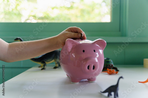 Boy (4-5) putting coin into piggy bank, close up