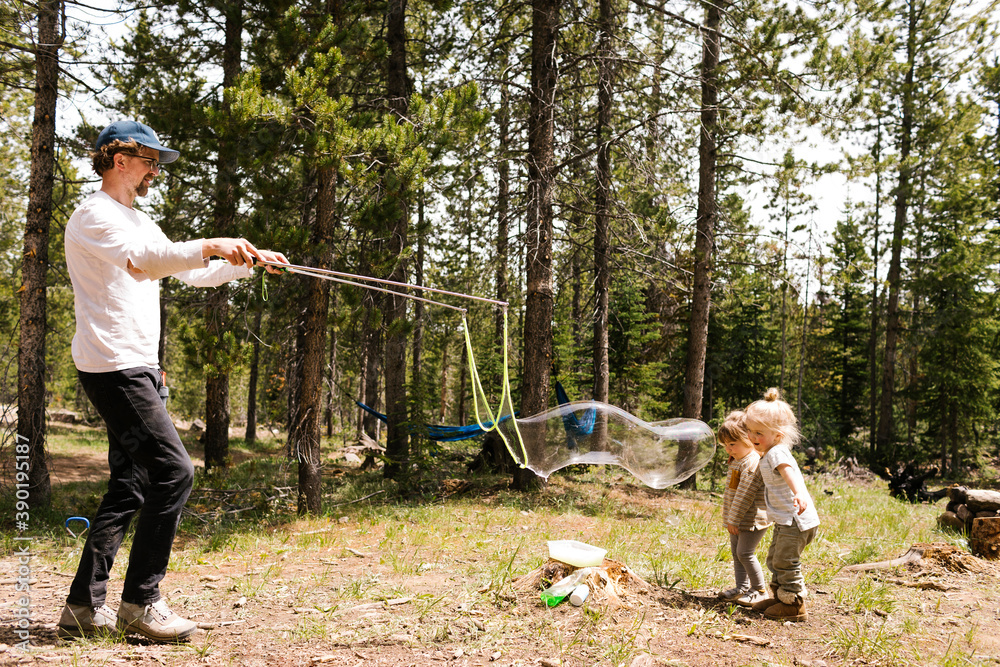 Father making large soap bubbles in forest for two daughters (2-3, 4-5), Wasatch-Cache National Forest Father making large soap bubbles in forest for two daughters (2-3, 4-5), Wasatch-Cache National Forest
