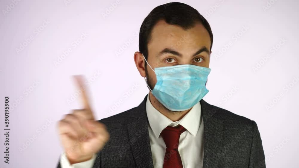 Handsome Man in Business Suit and Protective Medical Mask waving his finger over white background Handsome Man in Business Suit and Protective Medical Mask waving his finger over white background