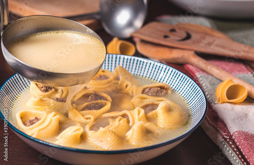 Primer plano de sopa de galets con una cuchara de sopa haciendo caer la sopa, el decorado está hecho con los utensilios de cocina photo