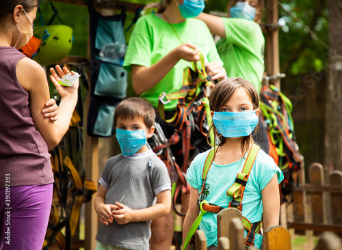 Children in masks standing in the equipping point in the sky rope park