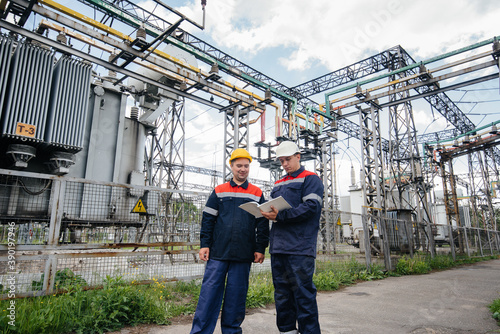 Two specialist electrical substation engineers inspect modern high-voltage equipment. Energy. Industry