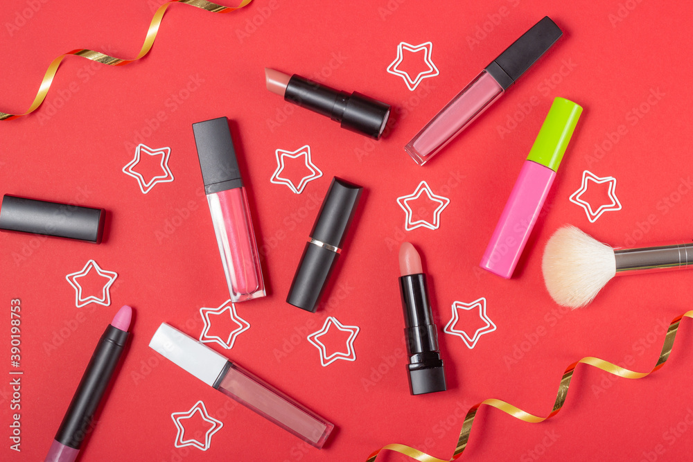 A set of cosmetics, lipstick and lip glosses, brush, mascara on a bright red background. The concept of buying cosmetics, online store, holiday A set of cosmetics, lipstick and lip glosses, brush, mascara on a bright red background. The concept of buying cosmetics, online store, holiday