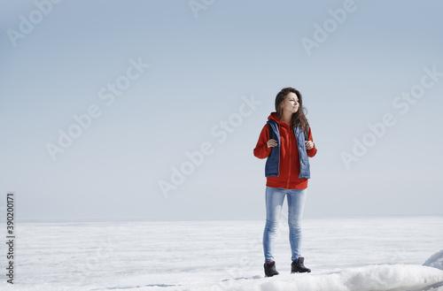 Young adult woman outdoors travelling in icy landscape with backpack