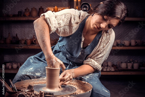 Beautiful artisan works with clay on a potter's wheel. Manual work. photo