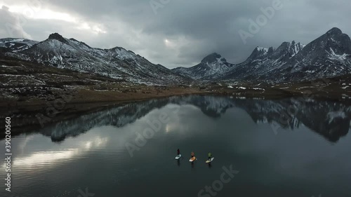 Drone view of a mountain landscape with a group of people paddle surfing