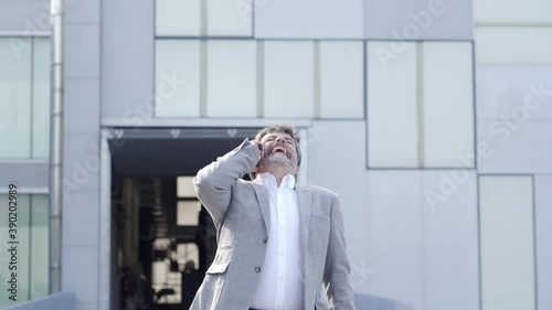 A happy businessman talks on the phone in front of his company
