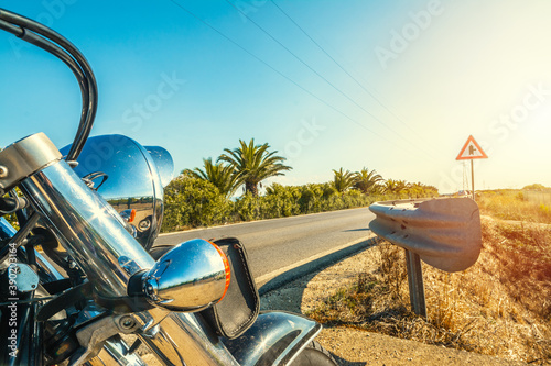 Close up of a classic motorcycle parked on the edge of a country road.