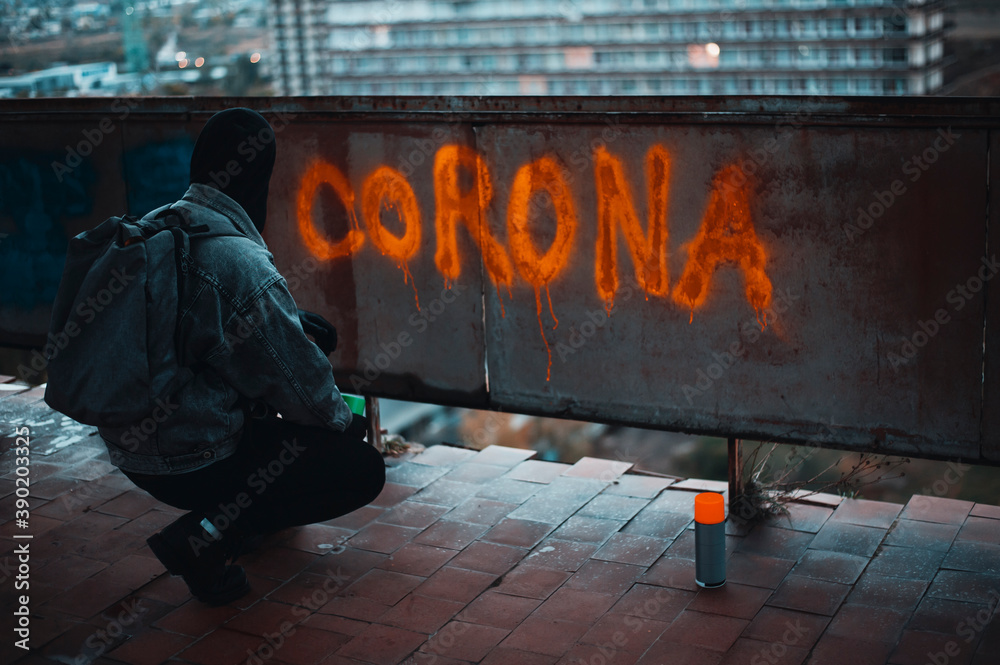 Naklejka premium Protester on the roof writes corona with spray paint 