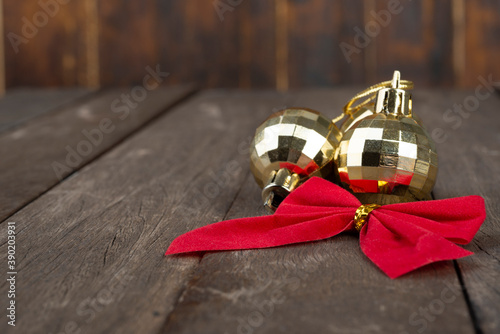 Golden christmas balls and red gift bow over wooden table with copy space © Odu Mazza