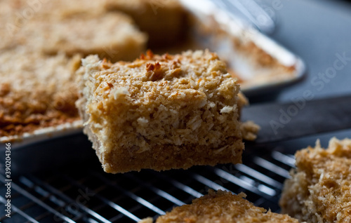 Close up of slice of sesame coconut bars on cooling rack