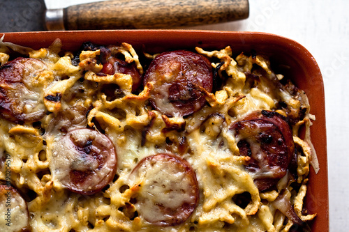 Overhead view of spaetzle with smoked kielbasa and caramelized onions served in tray photo