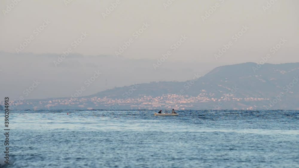 a motor boat with fishermen passes in the Messina strait in the warm hours of sunset with a motor boat with fishermen passes in the Messina strait in the warm hours of sunset with