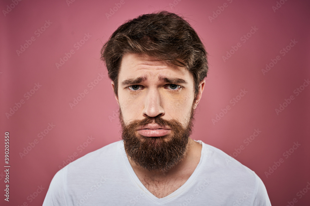 Obraz premium Emotional bearded man in white T-shirt discontent pink background