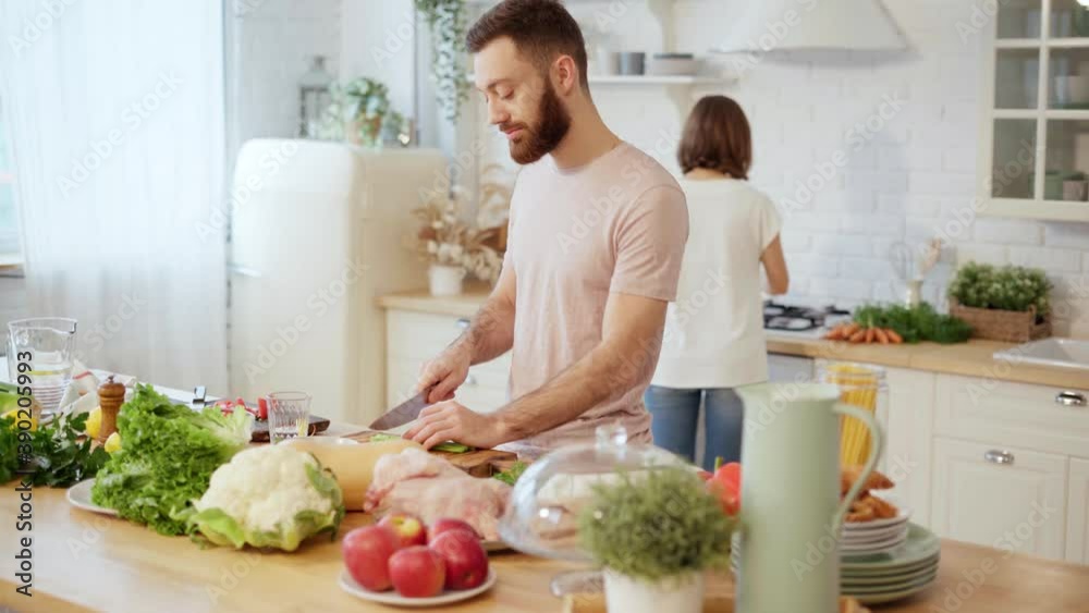 Young couple cooking together preparing dinner chopping vegetables and talking at home Young couple cooking together preparing dinner chopping vegetables and talking at home