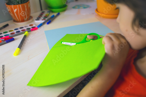 The child cuts colored paper, paper crafts photo