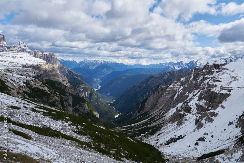 scenic view of a green rocky and snowy valley in the Dolomites in autumn 2020