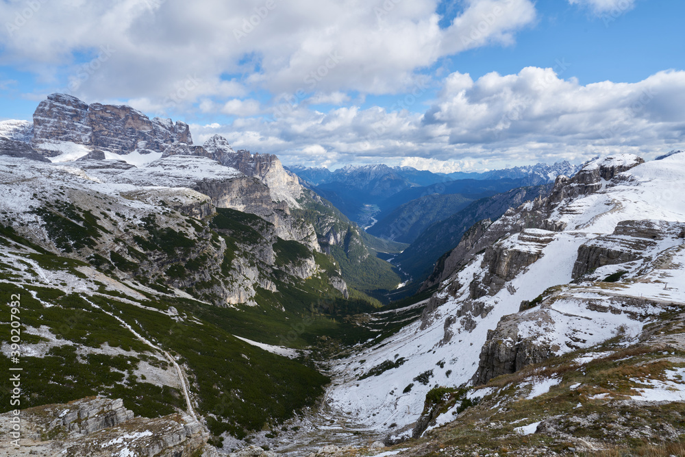 scenic view of a green rocky and snowy valley in the Dolomites in autumn 2020