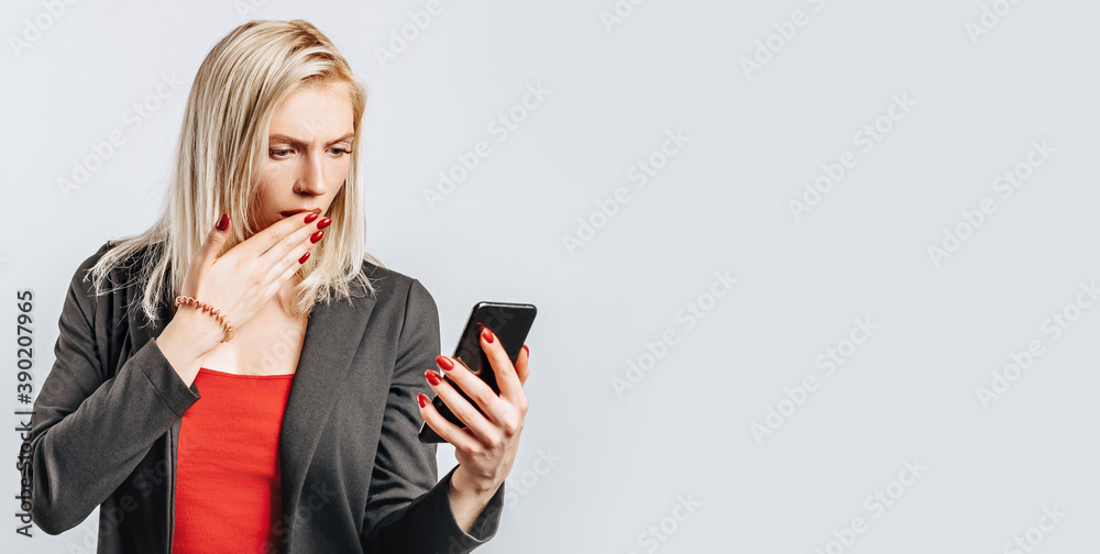 Beautiful young girl unhappy and holding phone on gray isolated background Beautiful young girl unhappy and holding phone on gray isolated background