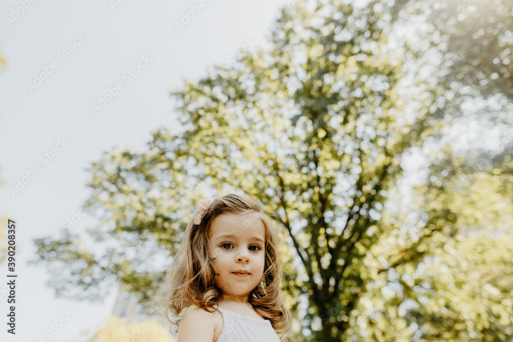 Young Girl Standing under a Tree at the Park Young Girl Standing under a Tree at the Park