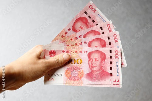 Hand holding one hundred Yuan notes against gray background photo